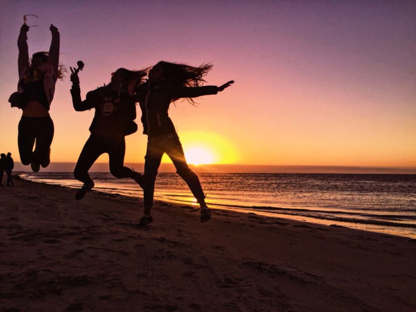 Des jeunes sautent sur la plage au coucher du soleil pendant un séjour linguistique en Australie